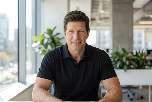 Professional corporate portrait of a man in a black polo shirt in a modern office